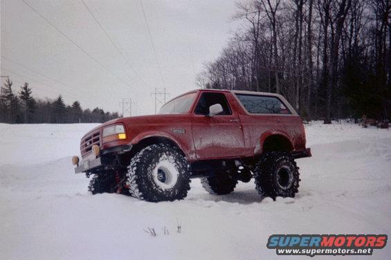 Red 1995 Ford Bronco with large tires in snow