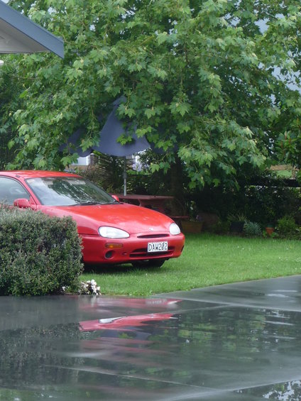 Red 1993 Mazda MX-3 coupe with license plate DAW282 parked on grass