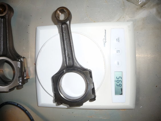 Two engine connecting rods on a digital scale reading 6.95 lbs