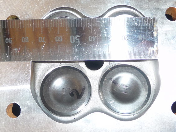 Engine cylinder head with two valves visible, measured by a metal ruler