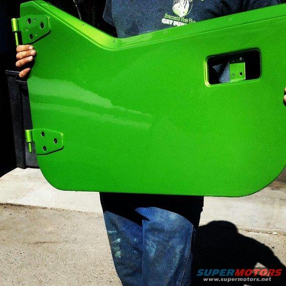 Person holding a bright green Jeep door with hinges attached