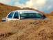 2007 Ford Crown Victoria - A 2007 Ford Crown Victoria is seen stuck in a dirt embankment under a cloudy sky.