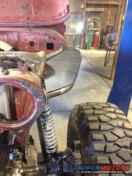 1985 Jeep CJ7 front end with custom roll cage tubing and large off-road tire. Suspension and frame are visible