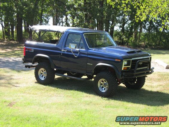 Blue Ford Bronco with a soft top, lifted suspension, and aftermarket bumper