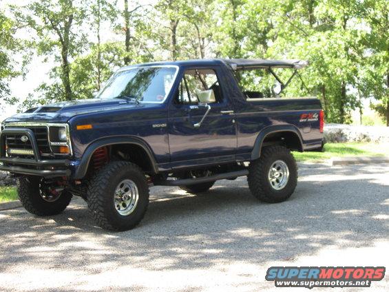 Dark blue Ford Bronco with a lift kit and off-road tires parked outside