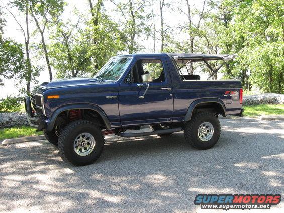 Blue Ford Bronco with a soft top, lifted suspension, and off-road tires parked on asphalt