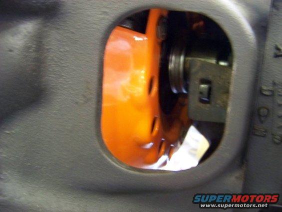 Close-up of an orange engine component visible through a gray housing