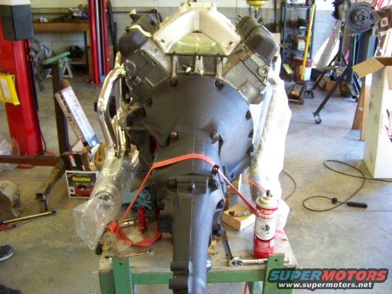 Engine and transmission assembly on a stand, with chrome headers and a red strap