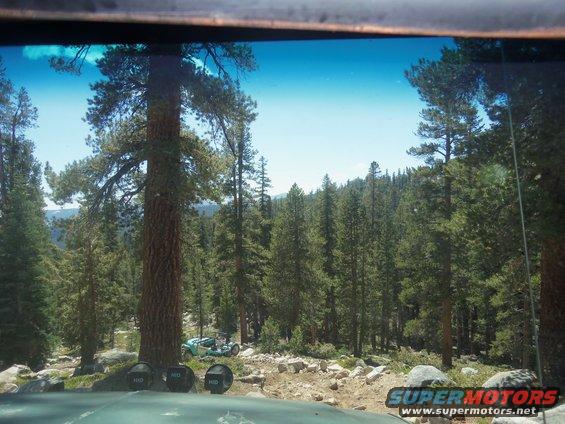 Light blue dune buggy parked on rocky terrain in a forest