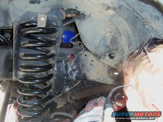 Close-up of a vehicle's front suspension coil spring and frame components