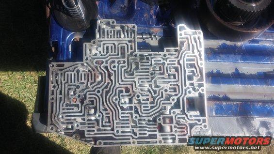 close-up of a complex metal plate with many channels and holes, likely a transmission valve body