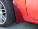 1993 Mazda MX-3 - Close-up of a red car's side panel, showing a mud flap and wheel.