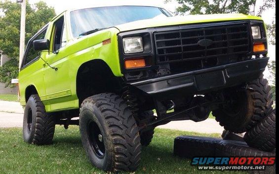 Lifted lime green Ford Bronco with big tires, front end angled up