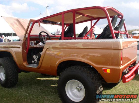 Customized Ford Bronco with red roll cage, flame decals, and off-road tires