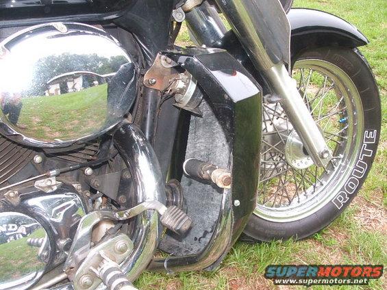 Close-up of motorcycle engine, chrome air cleaner, and front wheel with 'ROUTE' on tire