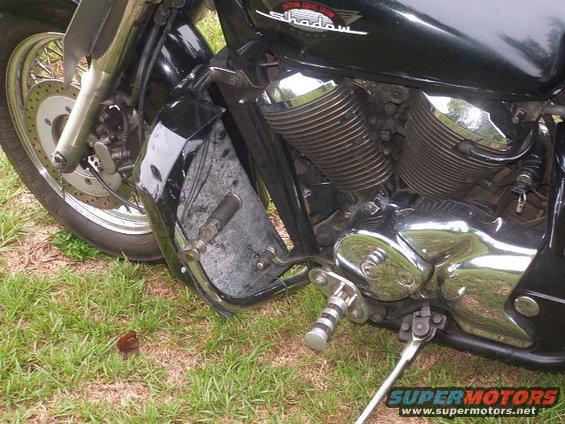 Motorcycle engine and front wheel, black paint, chrome accents, parked on grass