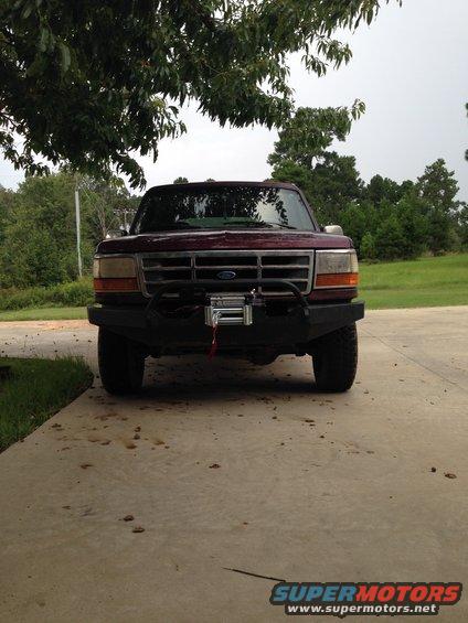 Maroon Ford truck with aftermarket bumper and winch, front view