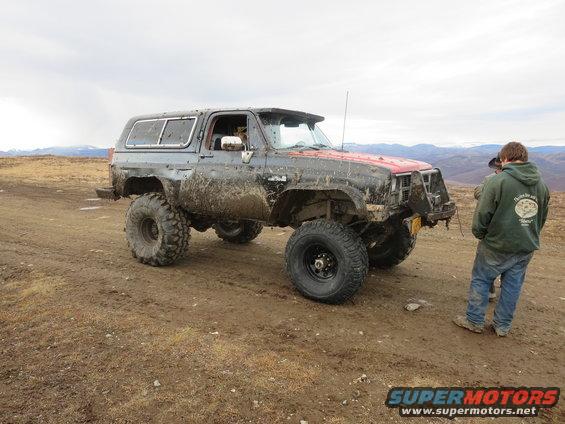 Muddy SUV with large tires and red hood