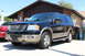 2003 Ford Expedition - A black 2003 Ford Expedition with tan trim is parked in front of a house, with a red car visible to the left.