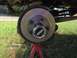 1979 Ford Bronco - A vehicle's wheel hub and brake rotor are shown, supported by a red jack stand on grassy ground.