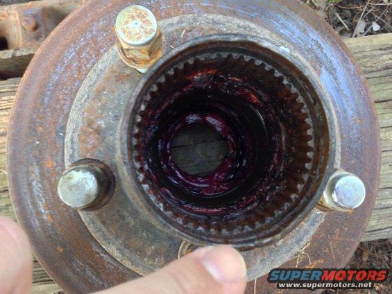 Rusty wheel hub with purple grease inside the splined opening, finger pointing
