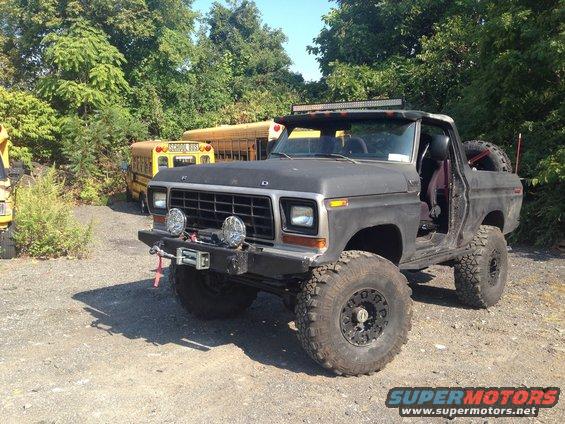 Black Ford Bronco with off-road tires, winch, and light bar, parked outdoors