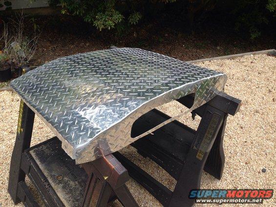 Diamond plate aluminum panel resting on black sawhorses outdoors
