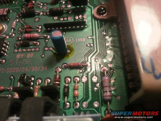 Close-up of a green circuit board with resistors, capacitors, and integrated circuits. Text reads 'MY 89' and '1988'