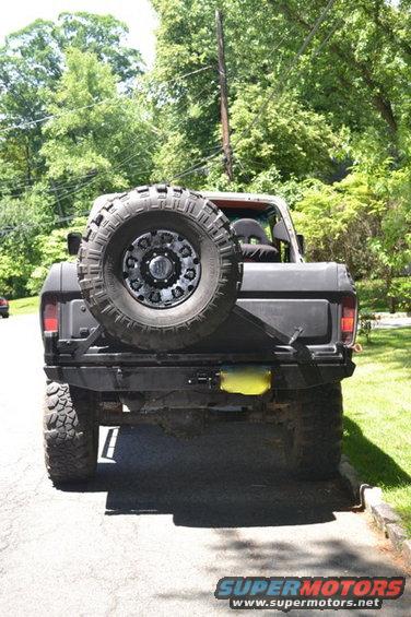 Black 1978 Ford Bronco rear view with spare tire mounted on tailgate, aftermarket bumper, and yellow license plate