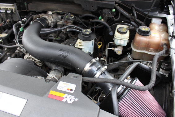 Engine bay with K&N air intake system and pink filter. Some fluid reservoirs are visible