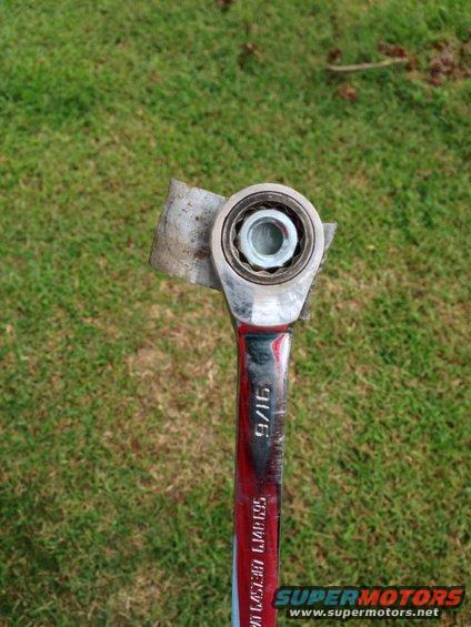 Ratchet wrench with a bearing attached to its head, set against a grassy background