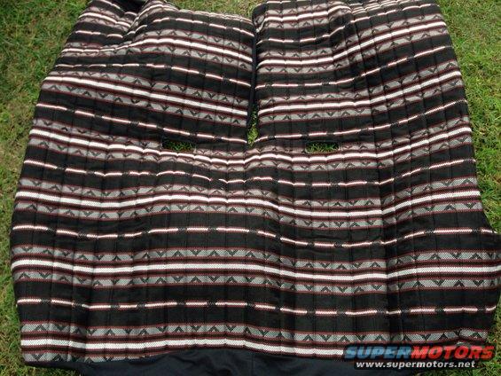 Two patterned seat covers with horizontal stripes and geometric designs, laid on grass