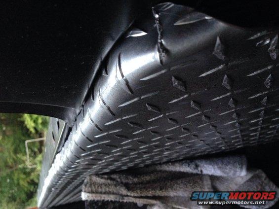 Diamond plate metal under vehicle, part view. Supermotors.net logo visible