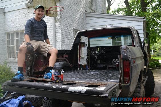Man in pickup truck bed, Supermotors logo visible