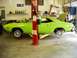 1974 Dodge Challenger - A lime green muscle car is being worked on in a garage, with its front wheels removed and hood open.