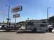 1997 Dodge 3500 - A white truck with a camper and boat trailer is parked near a Gallions store.