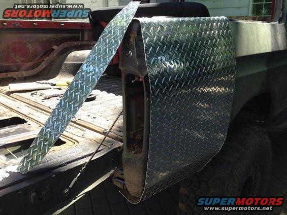 Diamond plate aluminum trim piece laid across the bed of a pickup truck next to the tailgate
