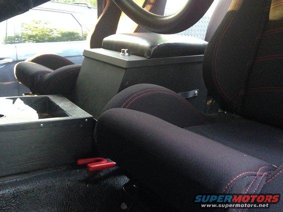 Interior shot of a vehicle, showing black seats with red stitching, a center console, and part of the steering wheel