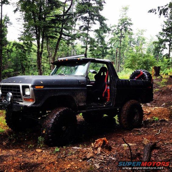Black Ford Bronco with lifted suspension and off-road tires parked in a wooded area