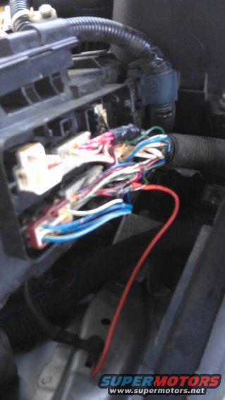 Close-up of a vehicle's engine wiring harness with exposed wires and connectors