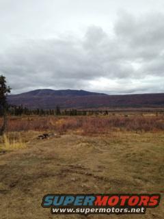 Overcast sky over a vast, empty field with distant hills