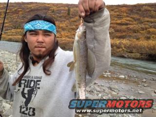 Man with bandana holding a fish, river in background