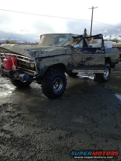 Muddy, damaged truck with a red gas can on the front and a roll bar