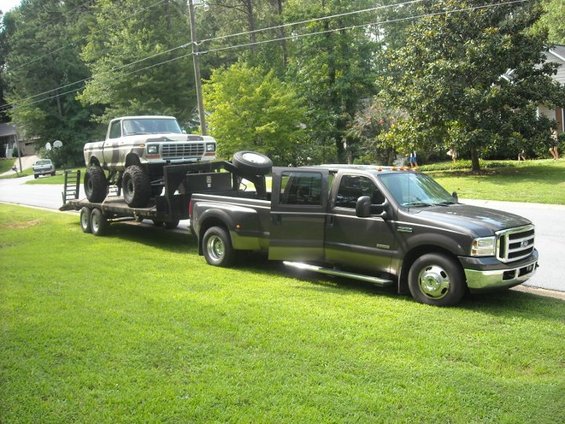 1979 Ford F-150 on trailer towed by modern Ford Super Duty pickup