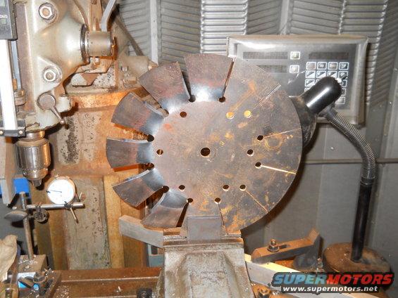 Metal fan blade with cutouts and holes, mounted on a machine