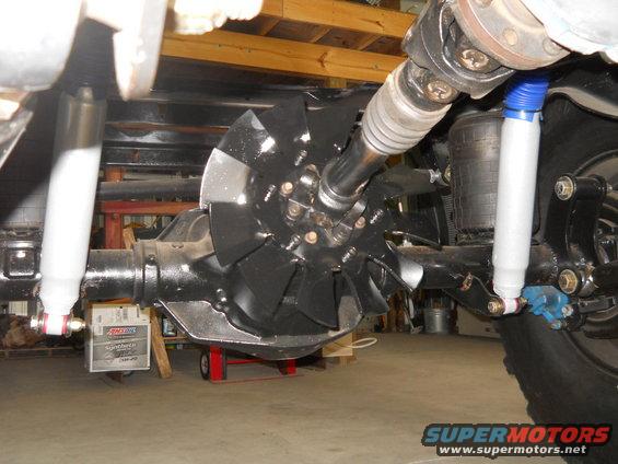 Undercarriage view of a vehicle's rear differential, driveshaft, and shocks. An Amsoil oil box is visible