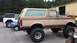 1988 Ford Bronco - A lifted Ford Bronco is parked in front of a workshop, with other vehicles nearby.