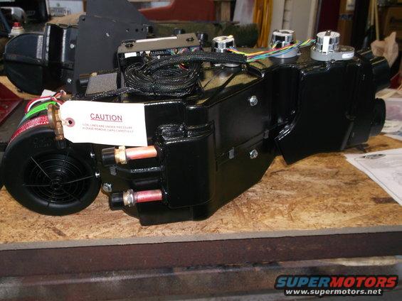 black automotive HVAC unit with caution tag and wiring
