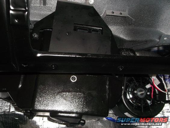 underbody of a vehicle showing black painted components and a fan with wiring