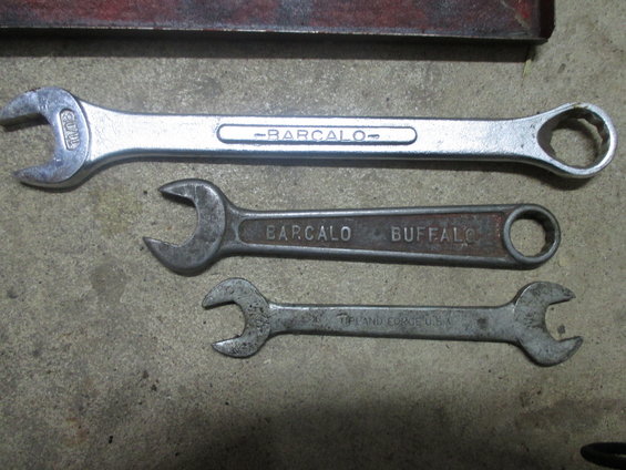 Three wrenches on a concrete surface. One is silver with 'BARCALO' on it. Another is dark metal with 'BARCALO BUFFALO' on it. The smallest is silver with 'TIFFANY FORGE U.S.A.' on it